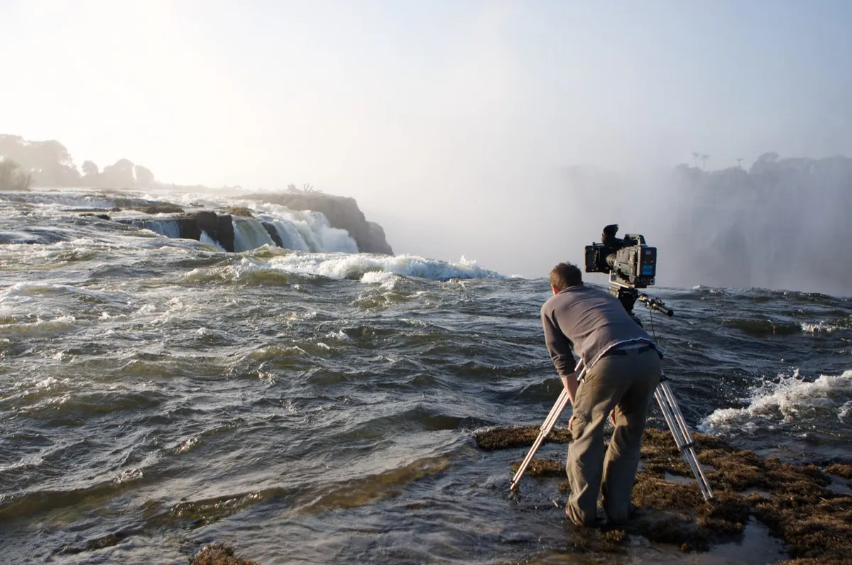 Camera operator on the rocks beside the rapids