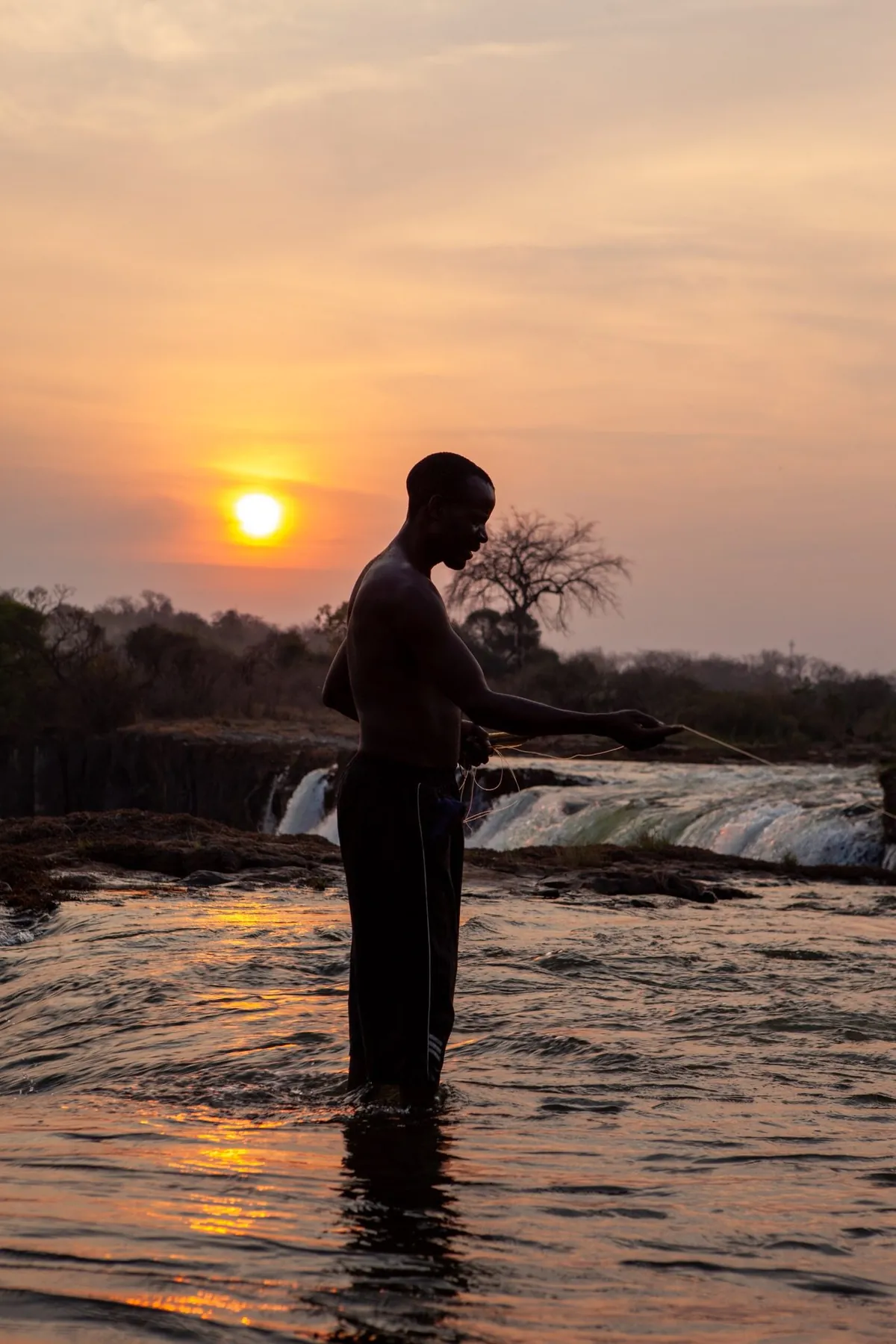 A lone figure in the river at dusk