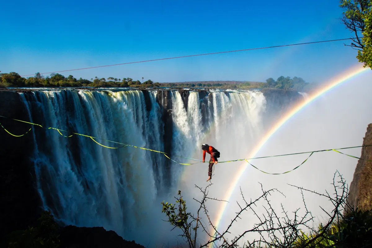 A slackline across the gorge with a rainbow in the spray